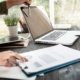 business-woman-hands-using-laptop-computer-placed-messy-office-desktop-scaled.jpg